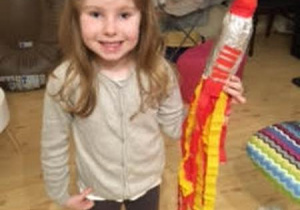 Uśmiechnięta dziewczynka trzyma kolorową rakietę